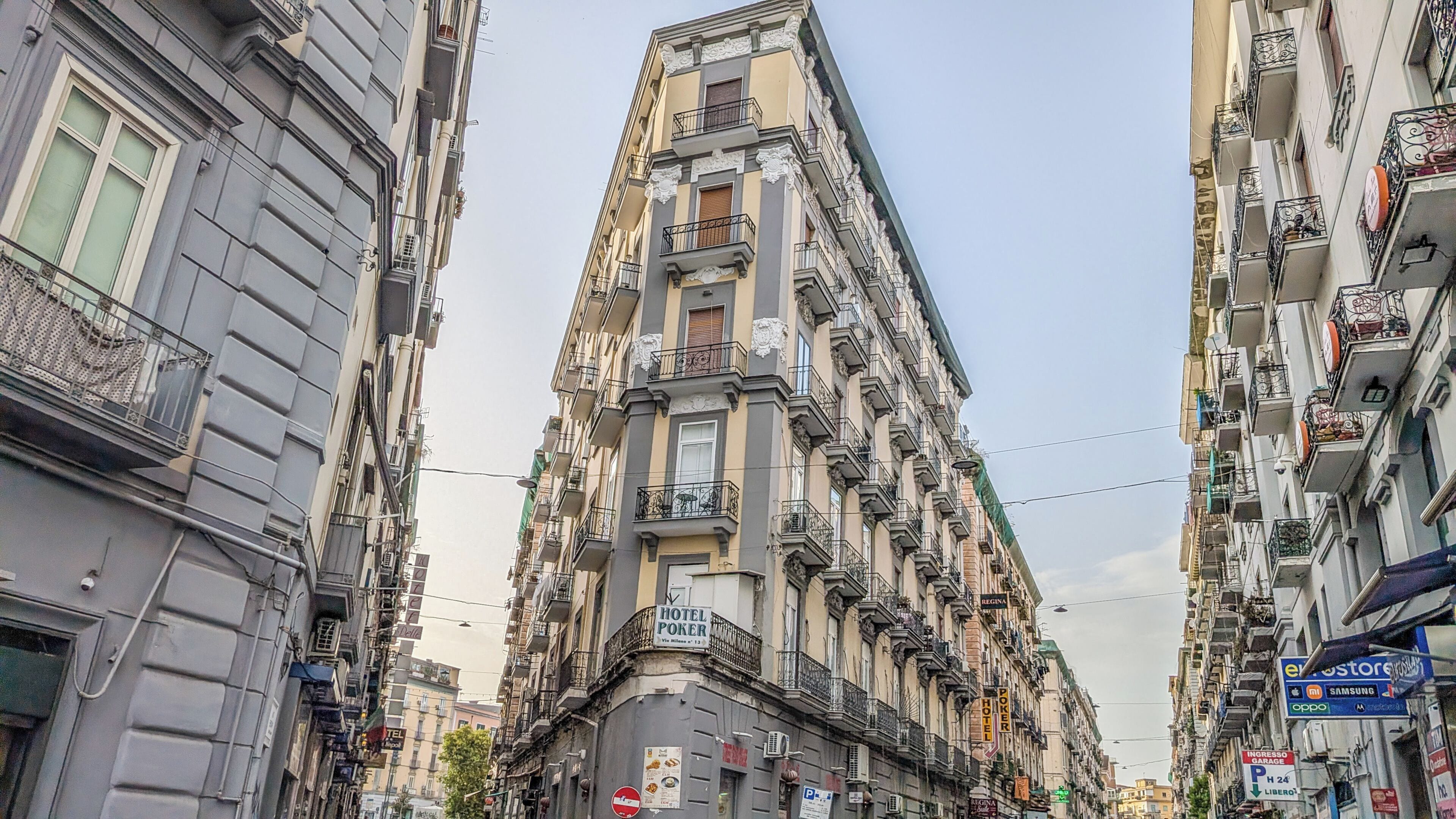 A multi-story building with balconies, a visible hotel sign, and various commercial signs.