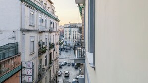 Una calle estrecha flanqueada por edificios, con un cartel que muestra la letra 'C' y automóviles estacionados.