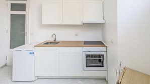 Una cocina compacta con un lavabo, un refrigerador pequeño, una estufa y un horno.