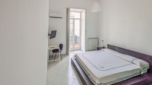 A bedroom with a bed, a desk, a chair, a radiator, and a window. - Residenza Edoardo (Napoli)