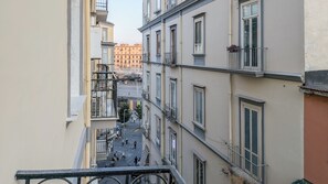 A narrow street between buildings with balconies, a visible fire escape, and pedestrians. - Residenza Edoardo (Napoli)