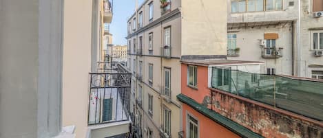 Un immeuble à plusieurs étages doté de balcons, d’une échelle de secours visible et d’un filet de sécurité vert sur le toit.