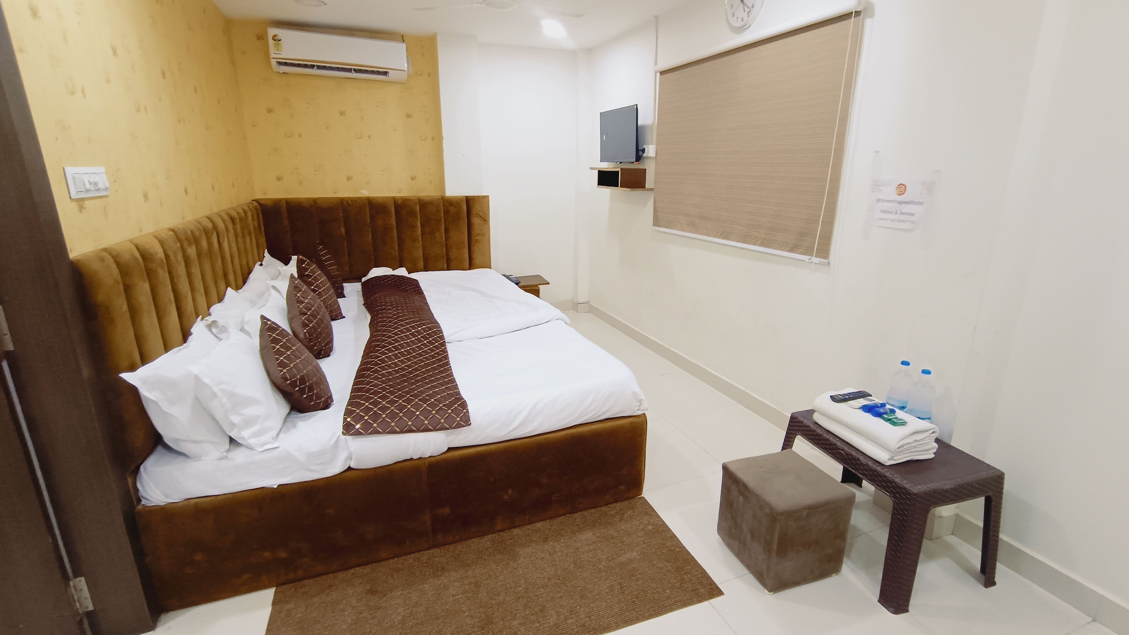 Quarto de hotel com cama, mesa de cabeceira e janela.
