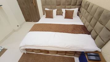A neatly made bed with a tufted headboard, two pillows, and a brown bedspread.