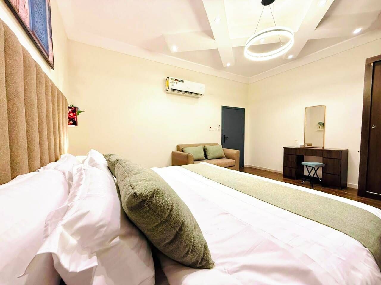 Een hotelkamer met een bed, een bureau, een stoel, een airconditioning en een deur.