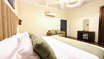 Een hotelkamer met een bed, een bureau, een stoel, een airconditioning en een deur.