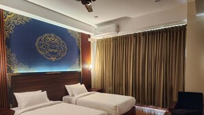 Habitación de hotel con dos camas, cabecero de madera, una pared decorativa grande y una ventana con cortinas.