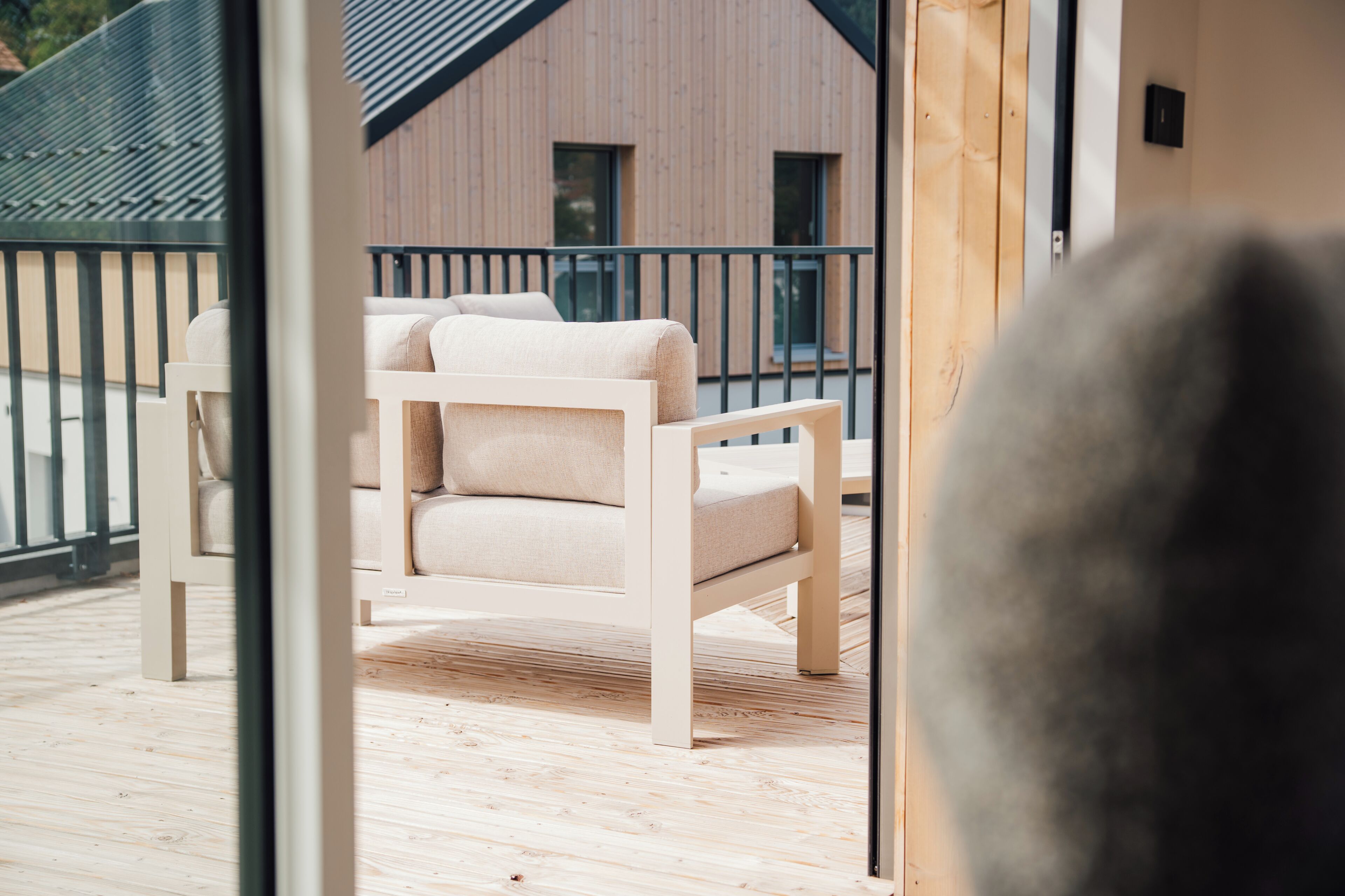 A wooden deck with a white chair and a building in the background.
