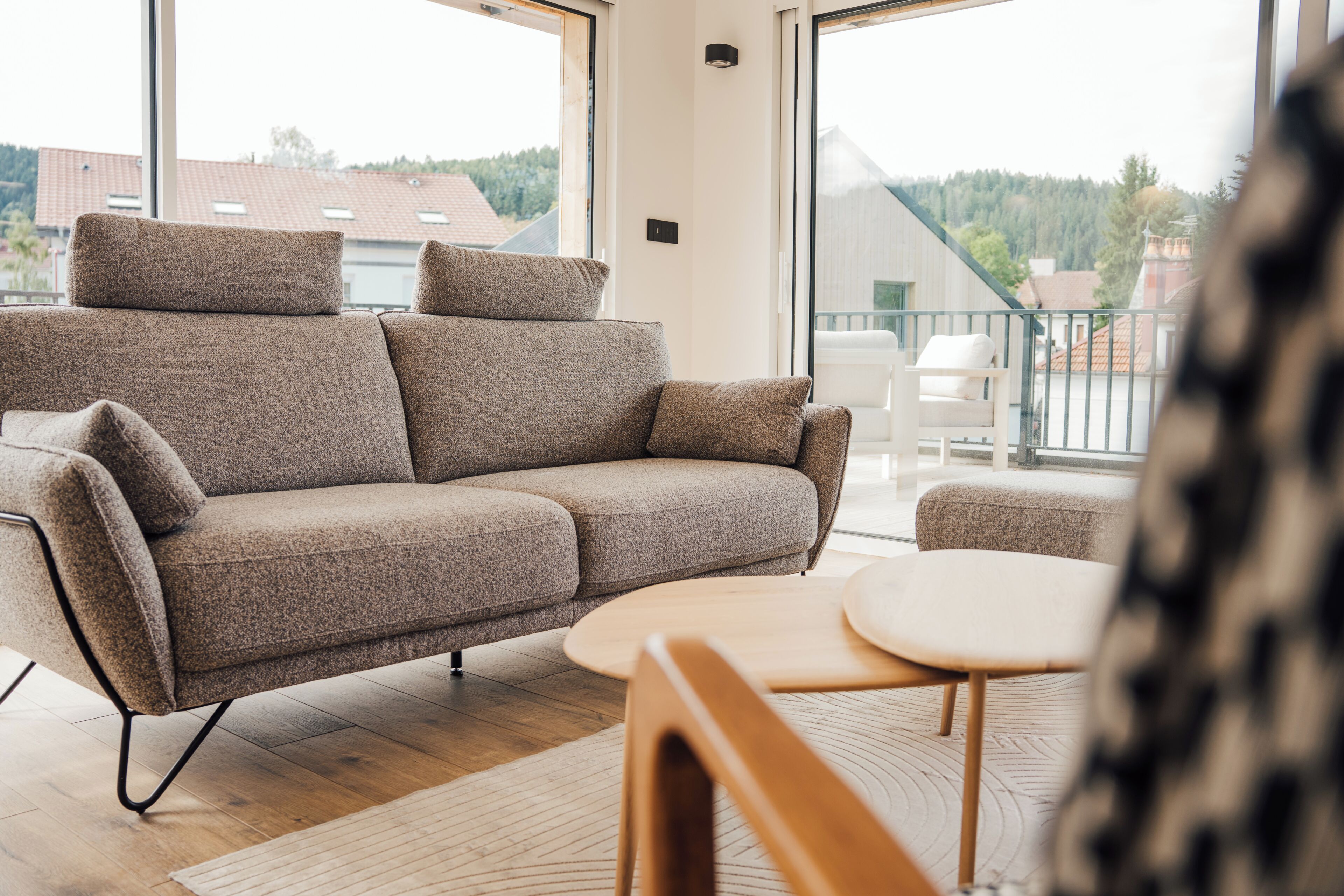 Una sala de estar moderna con un sofá, una mesita redonda y vistas al exterior a través de amplios ventanales.