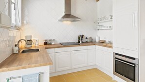 A kitchen with white cabinets, a wooden countertop, a built-in oven, and a window with blinds. - Holiday Home 'Paradise in Andalusia' with Mountain View, Wi-Fi and Air Conditioning (Tolox)