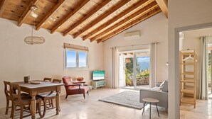 A spacious living area with a wooden ceiling, a dining table with chairs, a sofa, and a television. - Holiday Home 'Paradise in Andalusia' with Mountain View, Wi-Fi and Air Conditioning (Tolox)