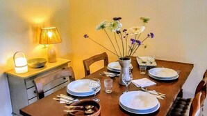 A dining area with a wooden table set for four, a vase with flowers, and a hanging light fixture. - Holiday Home 'Paradise in Andalusia' with Mountain View, Wi-Fi and Air Conditioning (Tolox)