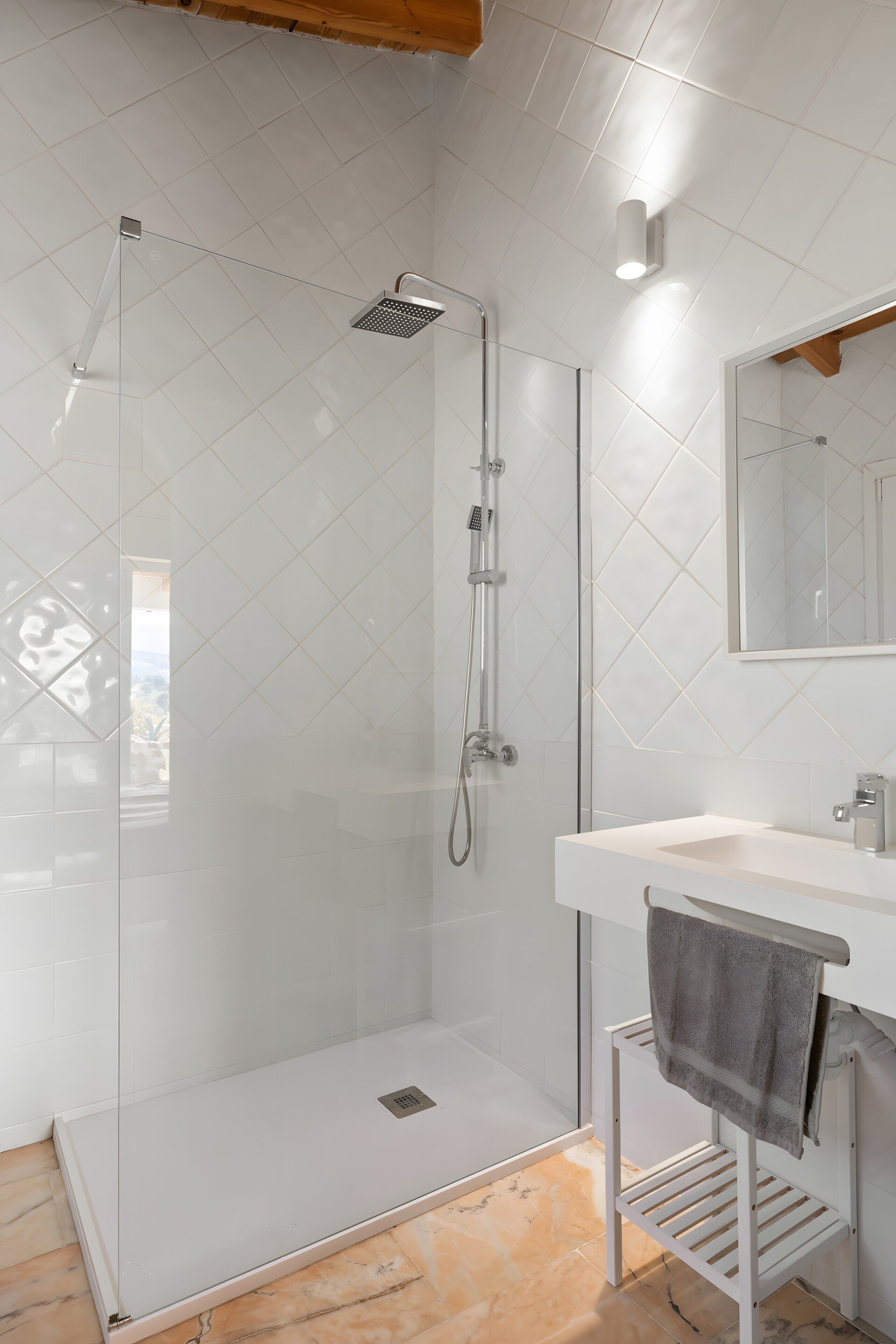 Un baño moderno con ducha de mampara de vidrio, un lavamanos blanco y un perchero para toallas.