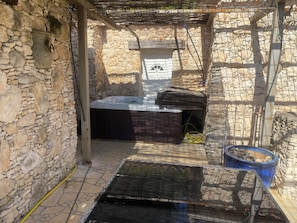 A stone-walled outdoor area with a hot tub and a covered seating area. - Casa Karine, with its terrace offering sweeping views, a hot tub, and a private barbecue in Olmeto (Olmeto)