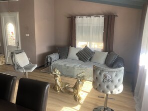 Ein Wohnzimmer mit einer Couch, zwei Sesseln, einem Glastisch und einer goldenen Statue.