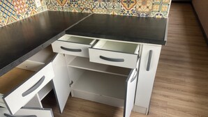 Uma cozinha com bancada escura, armários brancos e painel de parede com padrão.