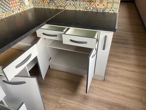 Eine Küche mit dunkler Arbeitsplatte, weißen Schränken und einer ornamentalen Rückwand.