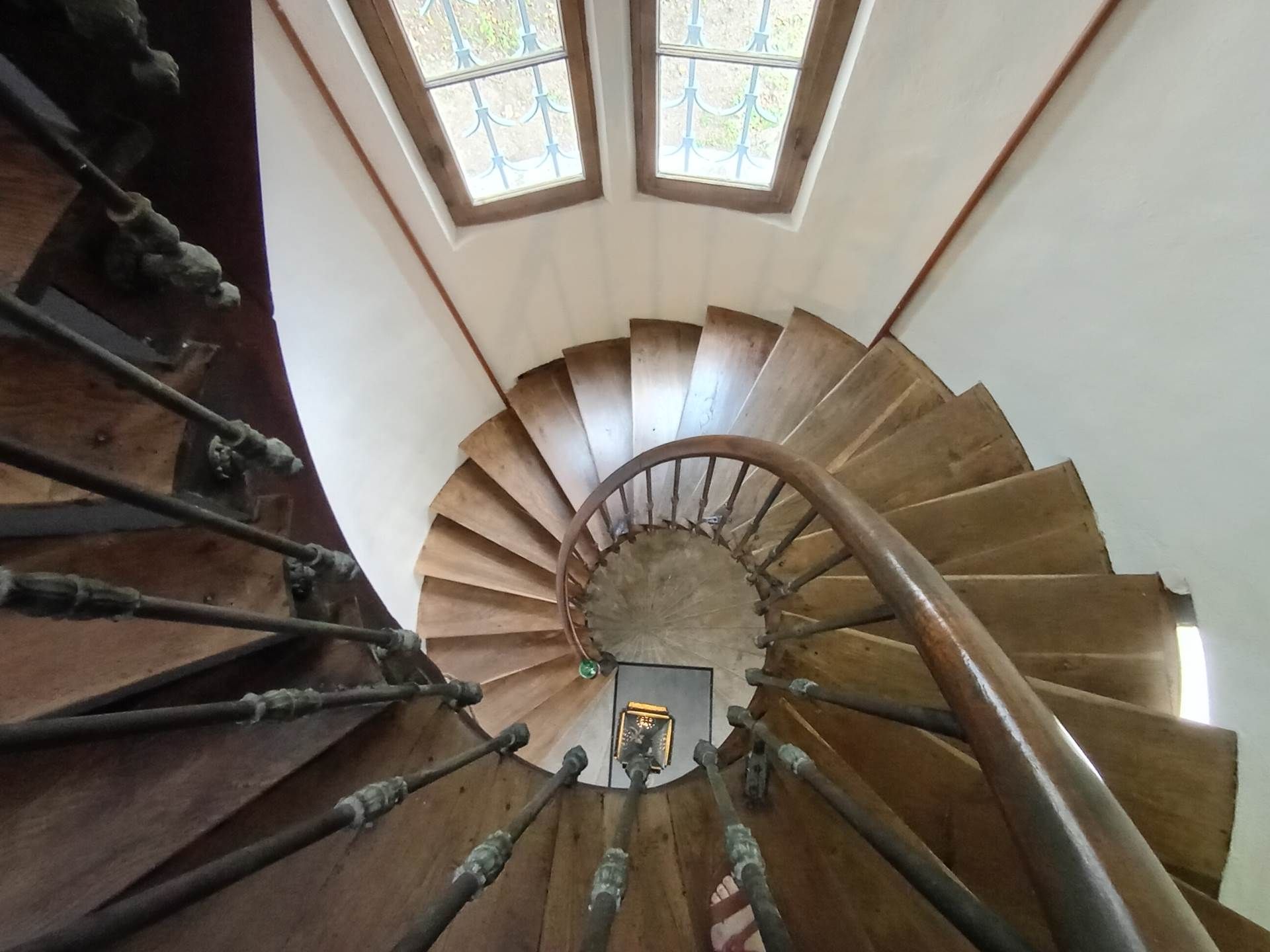 A spiral staircase with a wooden handrail and a metal balustrade.