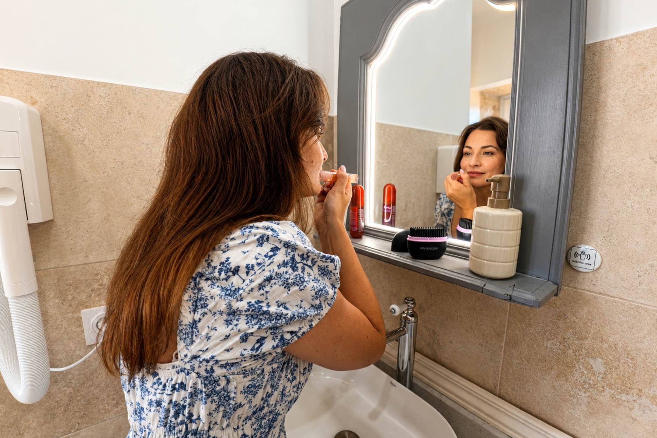 A person in a bathroom with a sink, mirror, and toiletries.