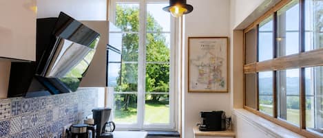 Una cocina con un ventanal grande, un mapa en la pared y una cafetera.