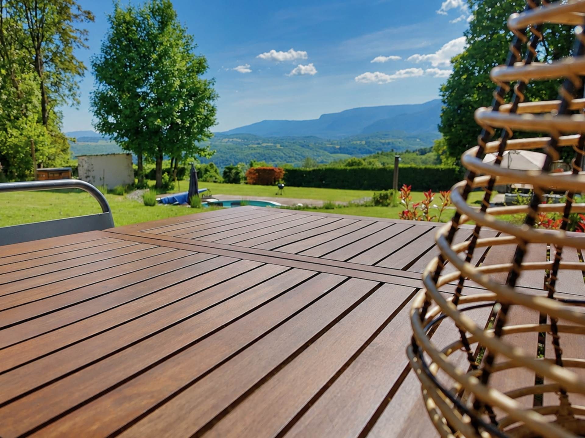 A wooden deck with a view of a pool and mountains.