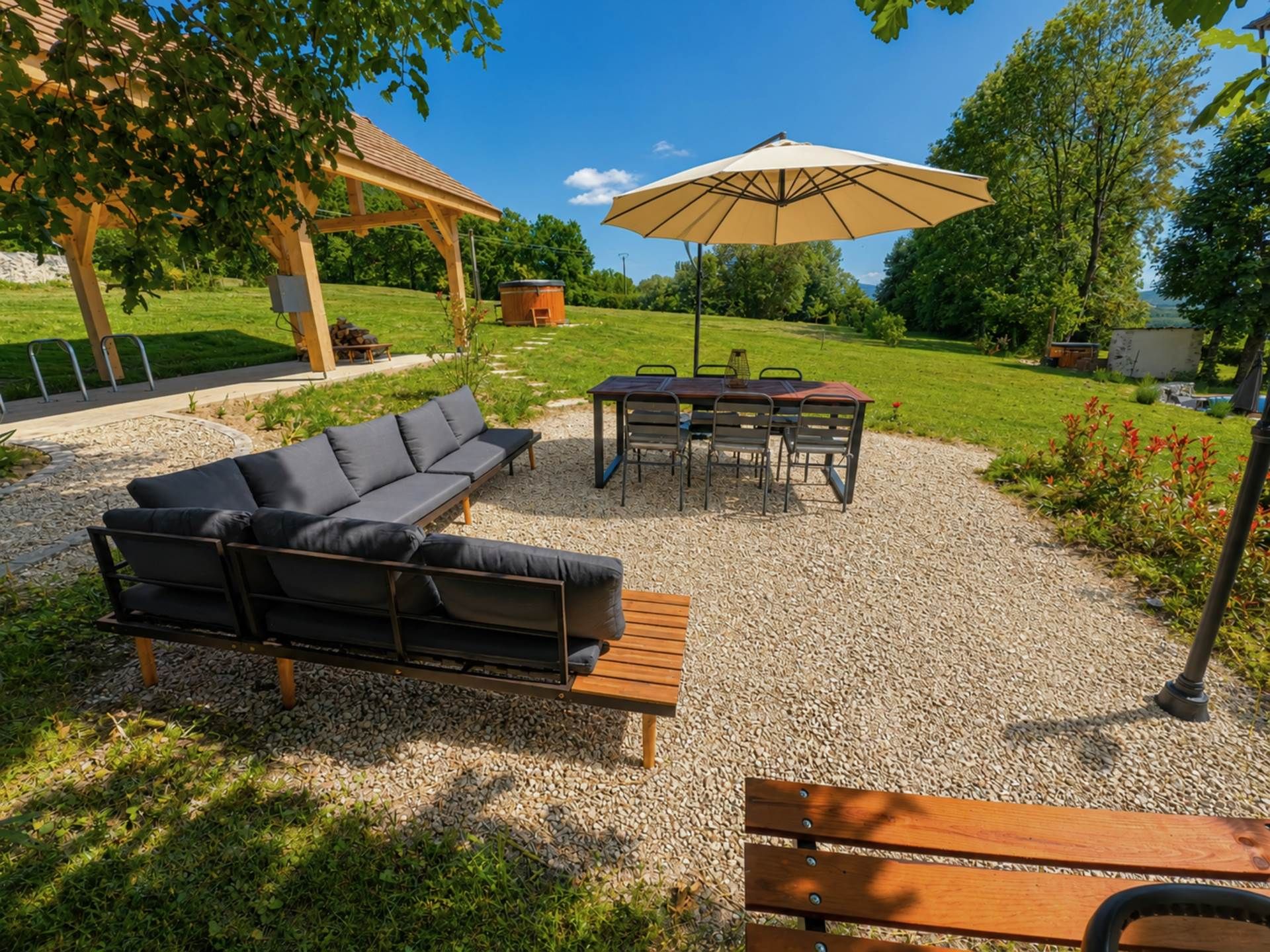 An outdoor seating area with a sofa, table, chairs, and an umbrella.