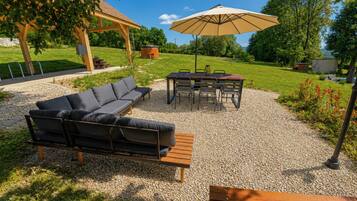 Un espace extérieur aménagé avec un canapé, une table, des chaises et un parasol.