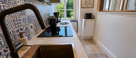 A kitchen with a stainless steel sink, a coffee maker, and a map on the wall.