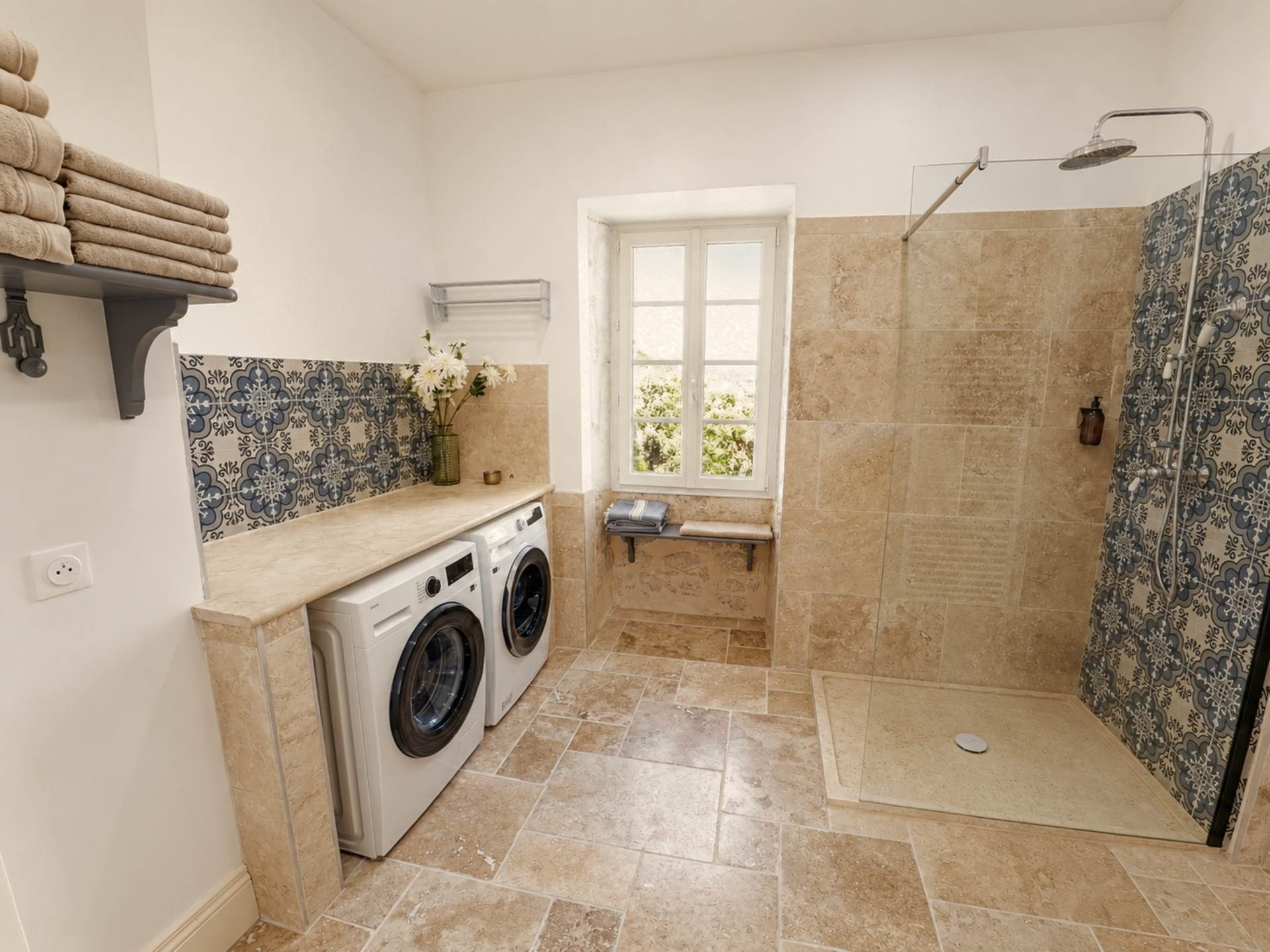 A compact bathroom with a shower, a washing machine, and a window.