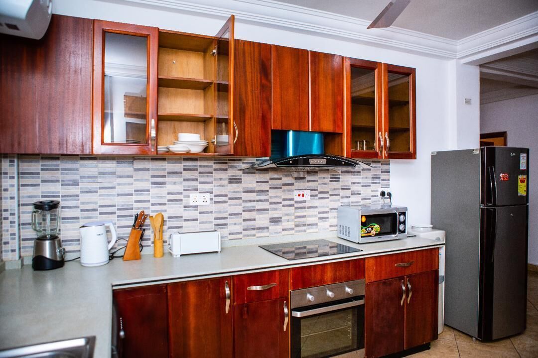 A kitchen with wooden cabinets, a microwave, a toaster, and a refrigerator.