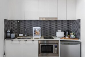 A compact kitchen with a microwave, oven, sink, coffee maker, and a small refrigerator. - Rooftop-Pool Studio Stay in Bondi (Bondi)