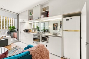 A modern kitchen with a built-in oven, microwave, and a large refrigerator. - Poolside Studio Retreat Near Oxford Street (Darlinghurst)