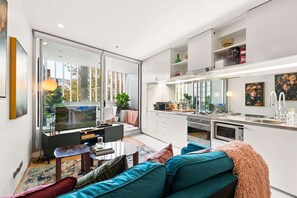 A modern apartment with a living room, dining area, and kitchen. - Poolside Studio Retreat Near Oxford Street (Darlinghurst)