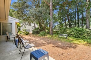 Eine Terrasse mit Gartenmöbeln, einer Bank und Blick auf ein bewaldetes Gebiet.