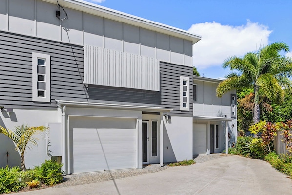 A two-story residential building with a garage, a covered entryway, and a driveway.