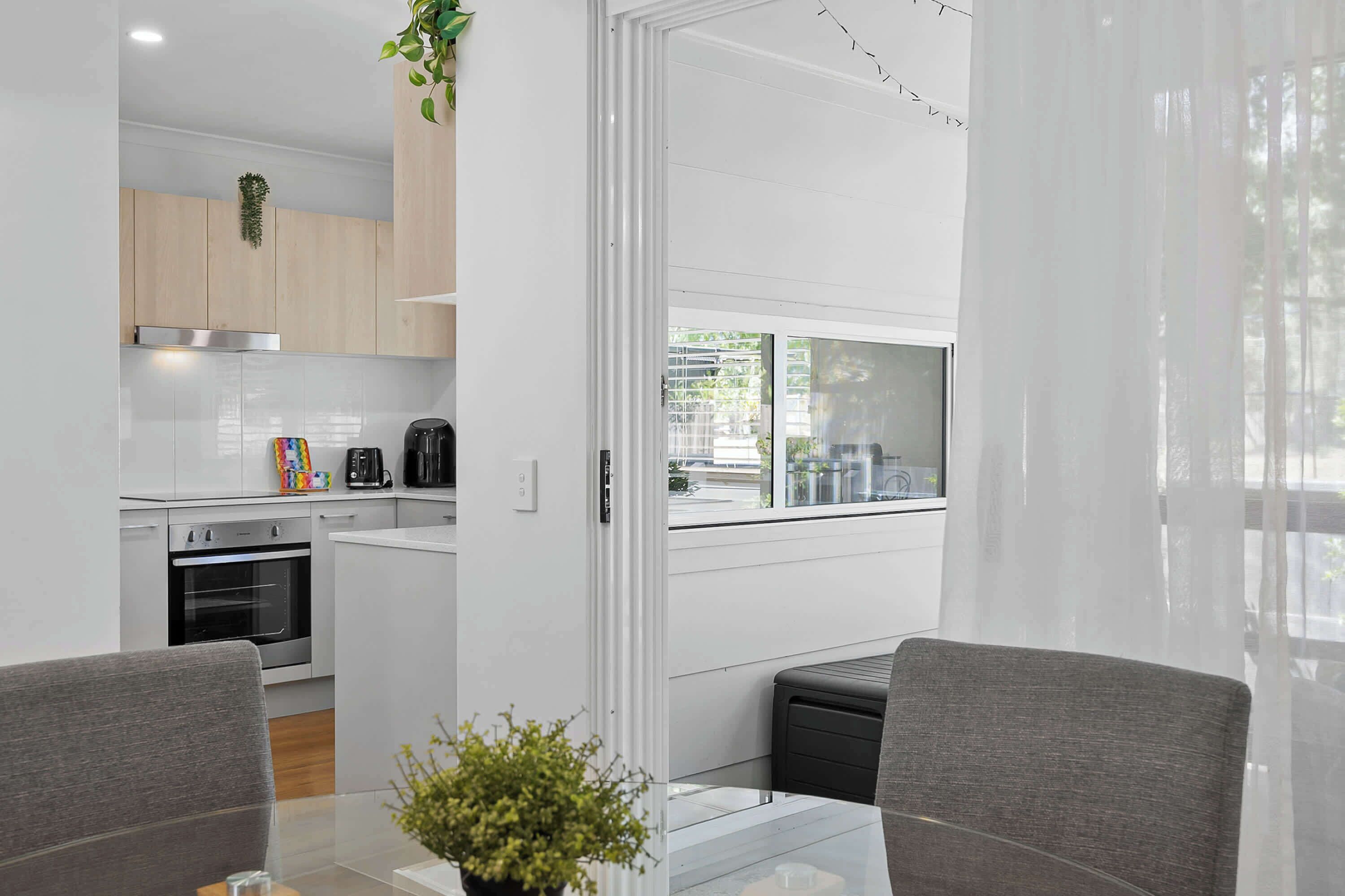 A modern kitchen with a built-in oven, a coffee maker, and a window overlooking a street.
