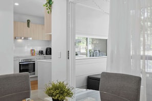 A modern kitchen with a built-in oven, a coffee maker, and a window overlooking a street.
