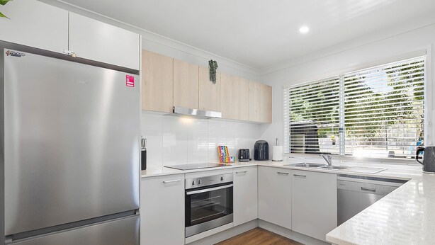Una cocina moderna con un refrigerador de acero inoxidable, horno empotrado y lavavajillas.