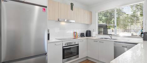 A modern kitchen with a stainless steel refrigerator, a built-in oven, and a dishwasher.