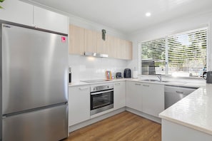 A modern kitchen with a stainless steel refrigerator, a built-in oven, and a dishwasher.