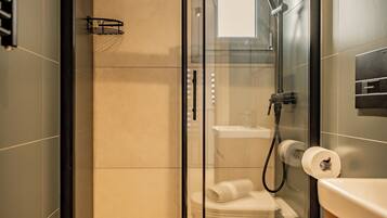 A modern bathroom with a glass-enclosed shower, a toilet, and a towel rack.