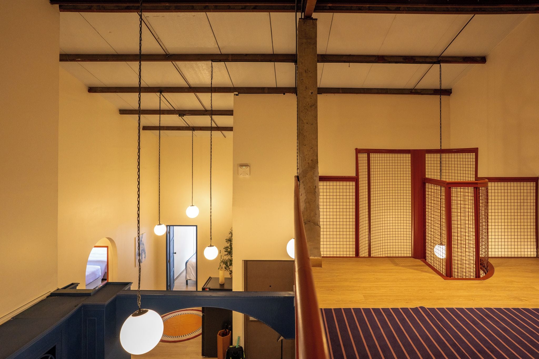 A hotel room with a wooden ceiling, a bed, a desk, and a view of a traditional Japanese room.