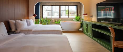 A hotel room with two beds, a bathtub, a TV, and a large window.