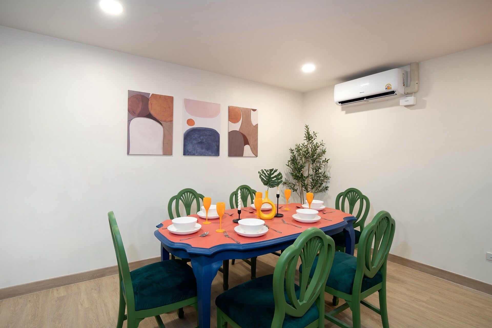 A dining area with a table set for four, surrounded by green chairs, and an air conditioning unit mounted on the wall.