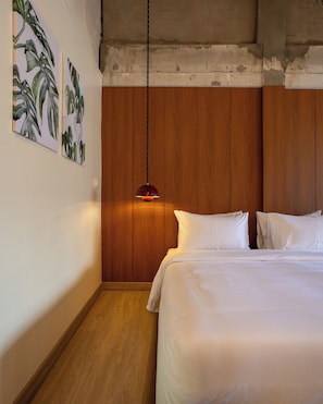 A bedroom with a wooden headboard, a hanging pendant light, and two white pillows. - KAIM Ekkamai (Bangkok)