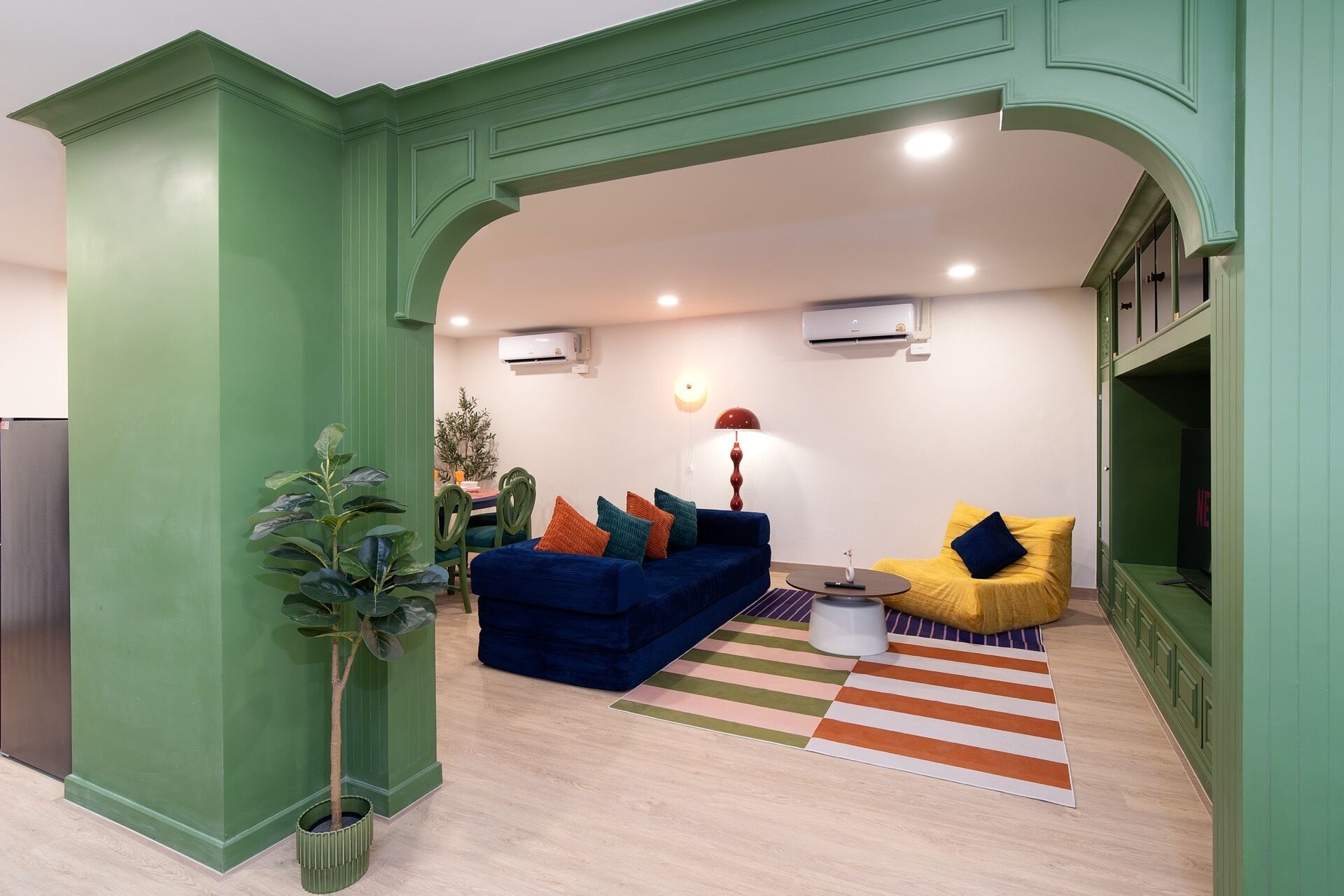 A living room with a blue sofa, a yellow chair, and a striped rug.
