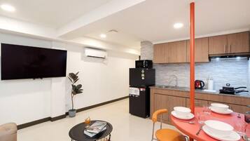 A modern kitchen with a flat-screen TV, a refrigerator, and a dining area with a table set for two.