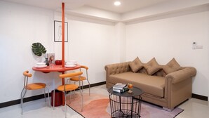Una sala de estar moderna con un sofá color beige, sillones naranja, una mesita redonda y un poste decorativo rojo.