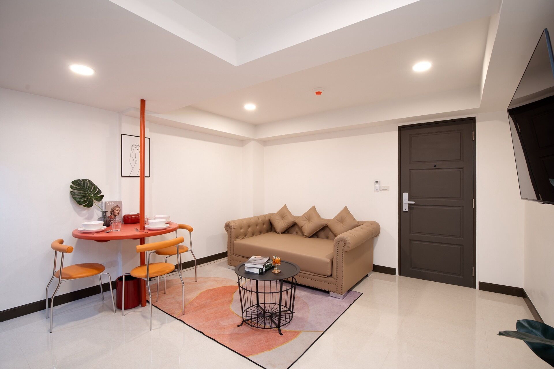 A modern living room with a sofa, a small round table, and a dining area with chairs and a table.
