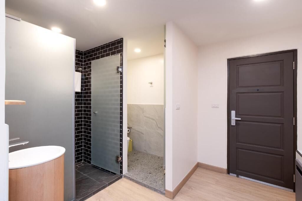 A bathroom with a white sink, a glass shower enclosure, and a dark brown door.